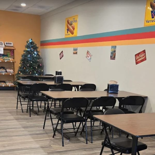 Interior of Funky Franks, a hot dog restaurant, with tables, chairs, and a decorated Christmas tree.