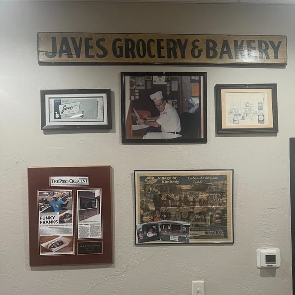 A wall display featuring a "Javes Grocery & Bakery" sign and framed articles about Funky Franks.