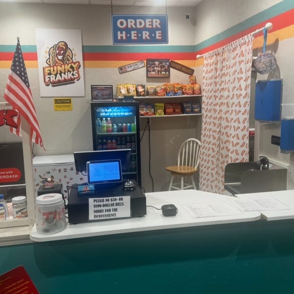 The Funky Franks hot dog restaurant counter with a "Order Here" sign and chip display.