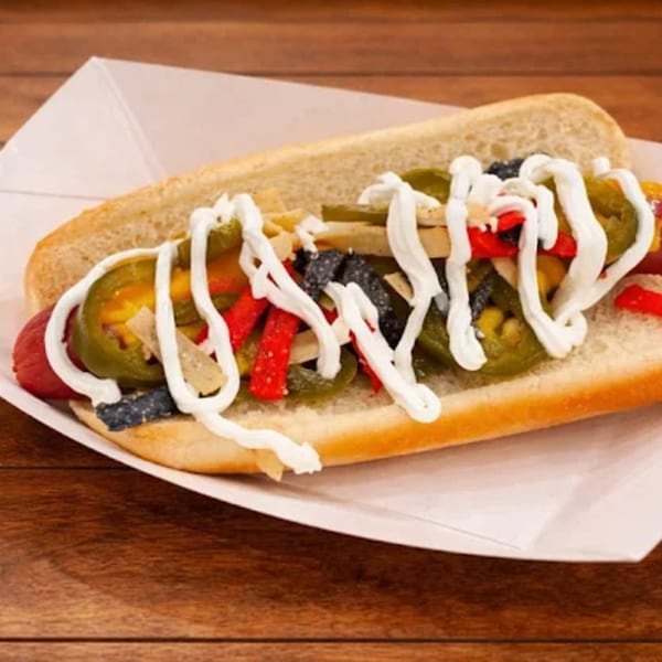 Funky Franks hot dog with jalapeños, red peppers, tortilla strips, and white sauce in a bun.